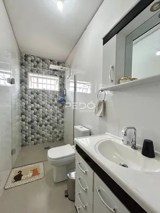 Foto de um banheiro com revestimento de parede e piso claro.