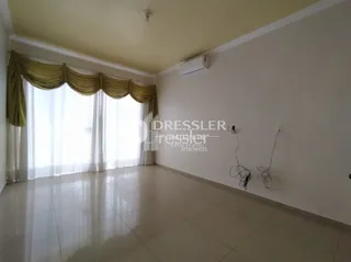 Ambiente interno com grandes janelas cobertas por cortinas claras.