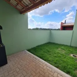 Vista externa do quintal com gramado e parede verde.