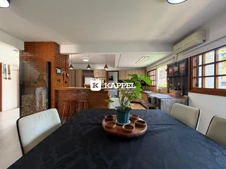 Interior de uma sala de jantar com parede de tijolos aparentes e vista para a cozinha.