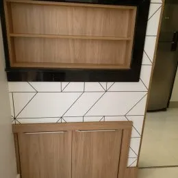 Parede interna com painel de madeira e revestimento geométrico branco em um imóvel.