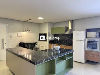 Cozinha moderna com ilha de granito escuro e eletrodomésticos em aço inoxidável.