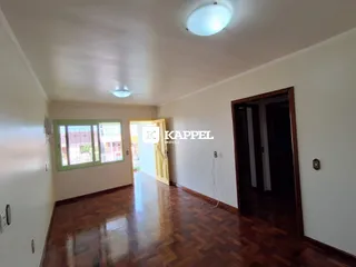 Hall de entrada com piso de madeira polida e parede branca.