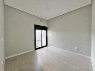 Interior de uma sala com piso de madeira clara e paredes brancas.