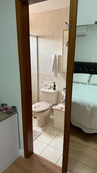 Banheiro com revestimento cerâmico e vista parcial do quarto.