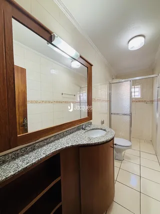Banheiro com revestimento cerâmico e bancada de granito.