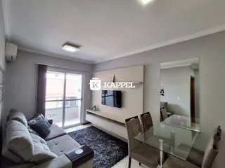 Sala de estar com sofá e televisão em um ambiente claro.