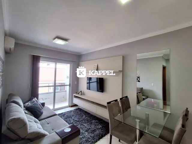 Sala de estar com sofá e televisão em um ambiente claro.