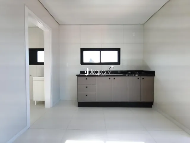 Interior de uma cozinha moderna com paredes brancas e piso claro.