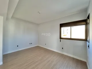 Ambiente interno de uma sala com piso de madeira clara e parede branca.