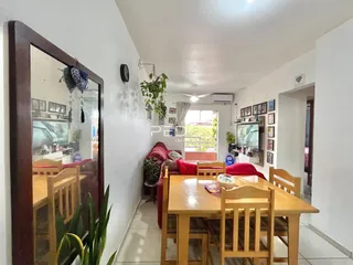 Ambiente interno de uma sala de jantar com mesa de madeira e paredes brancas.