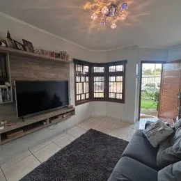 Sala de estar com televisão e painel de madeira na parede.