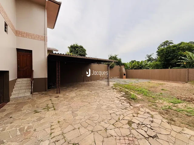 Fachada de uma residência com área coberta e pátio de pedra.