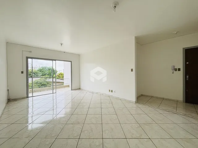 Ambiente interno amplo com piso de cerâmica claro e porta de vidro abrindo para o exterior.