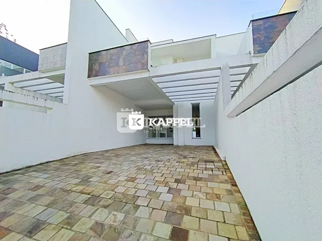 Fachada de uma residência moderna com pátio pavimentado de ladrilhos.