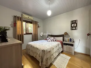 Quarto com piso de madeira e paredes brancas.