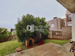 Vista externa de uma propriedade com jardim e parede de tijolos.