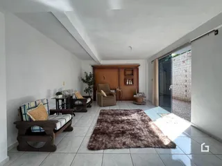 Sala de estar com piso de cerâmica e porta de vidro abrindo para o exterior.
