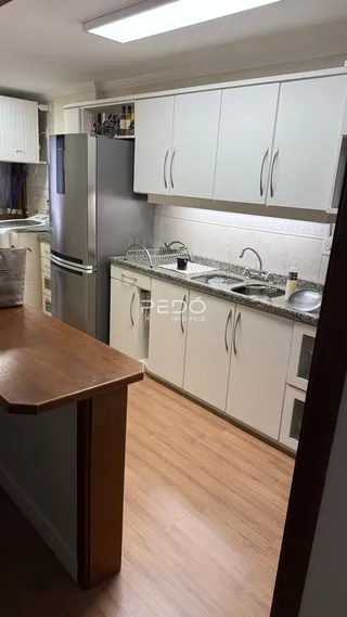 Vista da cozinha com armários brancos e bancadas claras.
