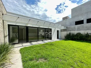 Fachada moderna de uma residência com grandes portas de vidro e gramado.