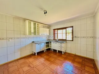 Foto de uma cozinha com armários brancos e piso de cerâmica.