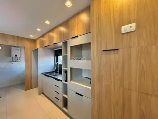 Corredor que leva a uma área de cozinha com armários de madeira.