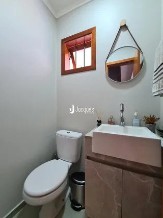 Foto de um banheiro com louças sanitárias e bancada em um imóvel.