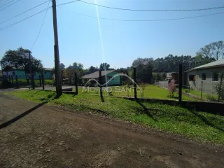 Vista externa de um terreno com grama e árvores sob um céu azul.