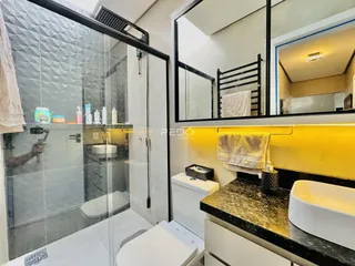 Foto de um banheiro com box de vidro e louças brancas.