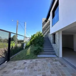 Área externa pavimentada com degraus e vegetação ao fundo.