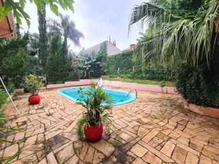Piscina e jardim com vegetação exuberante no quintal.