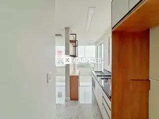 Vista de um corredor moderno com acesso a uma cozinha com bancada de aço inoxidável.