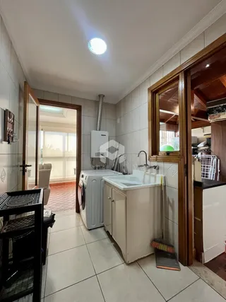 Interior da cozinha com piso de cerâmica e armários brancos.