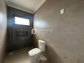 Foto de um banheiro com revestimento de cerâmica e louças brancas.
