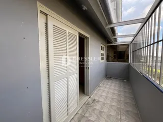 A foto mostra a entrada de um imóvel com piso de cerâmica e uma porta branca.