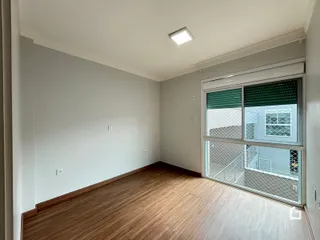 Sala de estar com piso de madeira e grande janela.