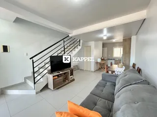 Sala de estar com sofá e escadaria em um apartamento moderno.
