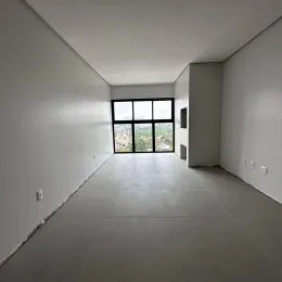 Corredor interno com paredes brancas e uma grande janela no final.