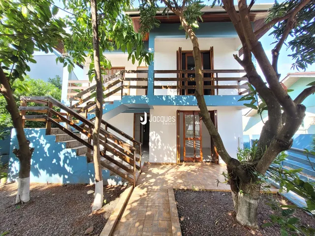 Fachada de uma casa em Lajeado, Brasil, com escadaria de madeira e vegetação ao redor.