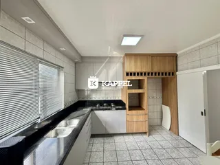 Cozinha moderna com armários brancos e bancada escura.