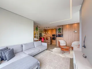 Sala de estar moderna com sofá cinza e acabamentos em madeira.