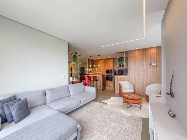 Sala de estar moderna com sofá cinza e acabamentos em madeira.