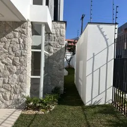 Fachada branca com base de pedra e jardim em uma residência.