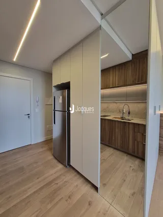Uma cozinha moderna com armários brancos e piso de madeira clara.