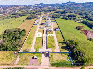 Vista aérea de uma propriedade rural com campos verdes e construções dispersas.