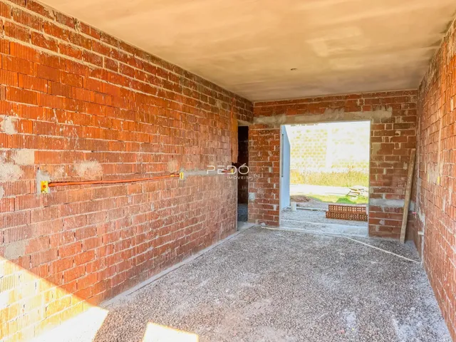 Uma parede de tijolos vermelhos com piso de concreto é visível no interior da propriedade.