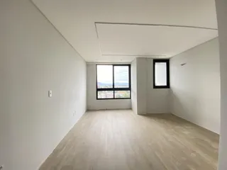 Sala de estar ampla com piso de madeira e janela com vista da paisagem urbana.