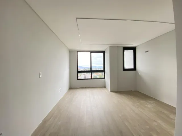 Sala de estar ampla com piso de madeira e janela com vista da paisagem urbana.