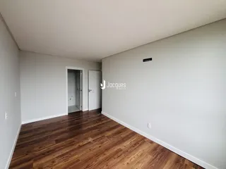 Interior de um ambiente com piso de madeira e porta de entrada.