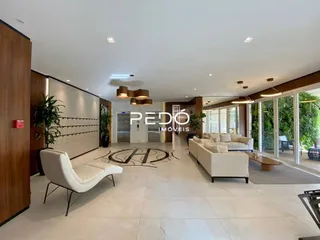 Sala de estar ampla com piso de cerâmica clara e móveis brancos.
